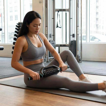 Kvinna masserar låret med Fitpaddy FitRoller sittande på en träningsmatta